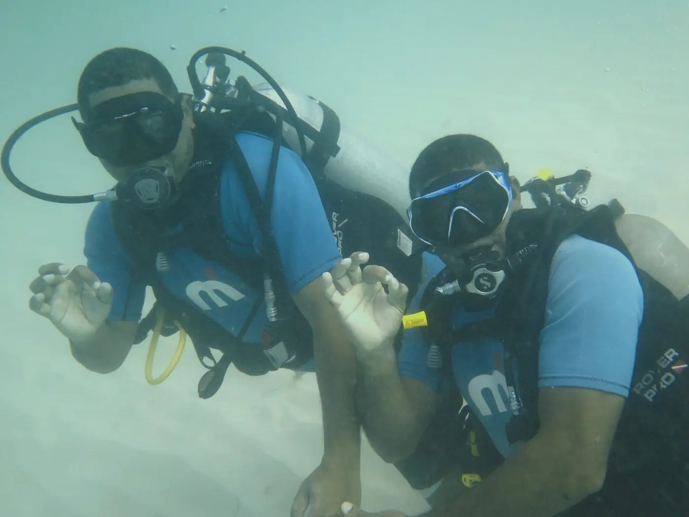 Two divers giving the OK sign over the sand