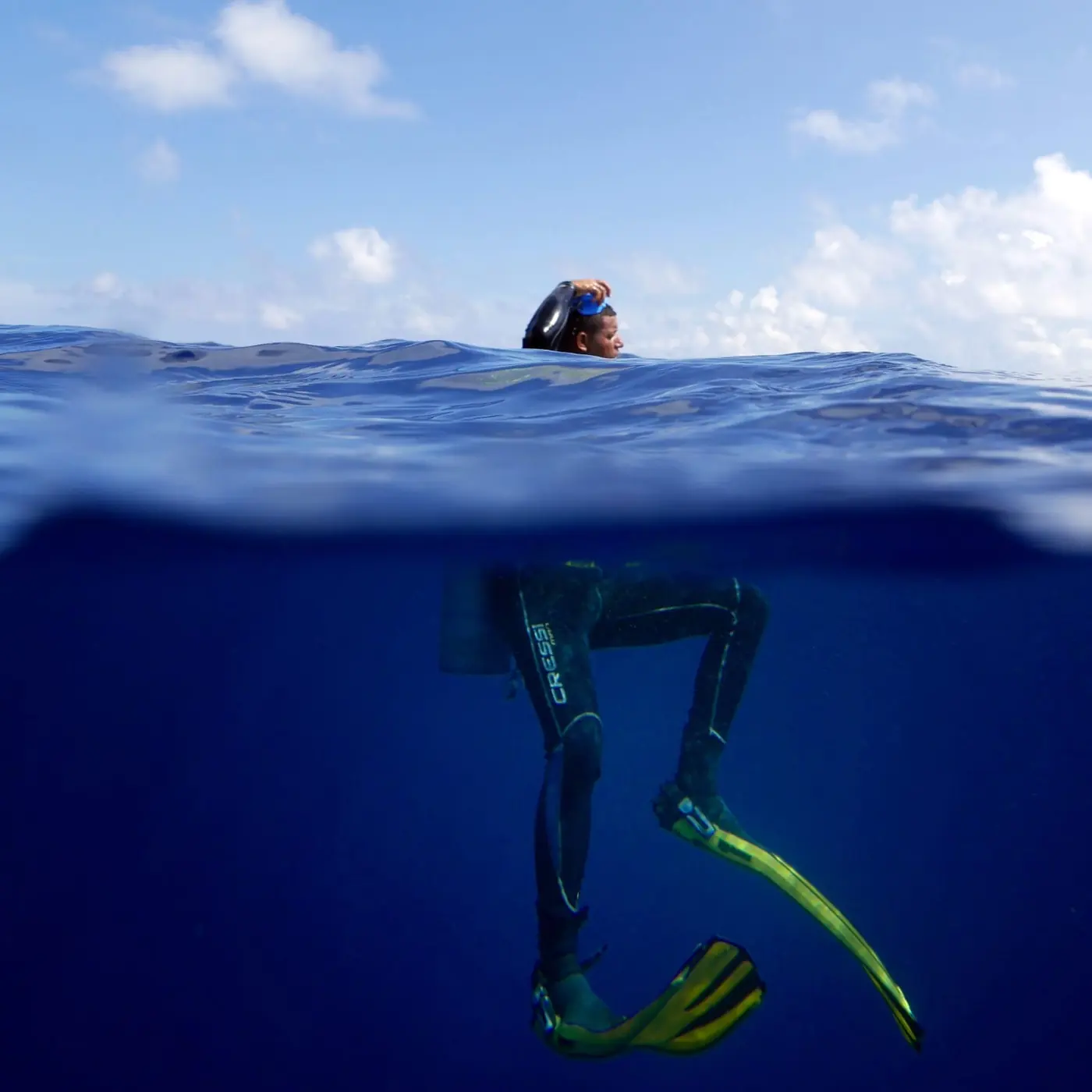 Diver at the surface, half above and half below the water