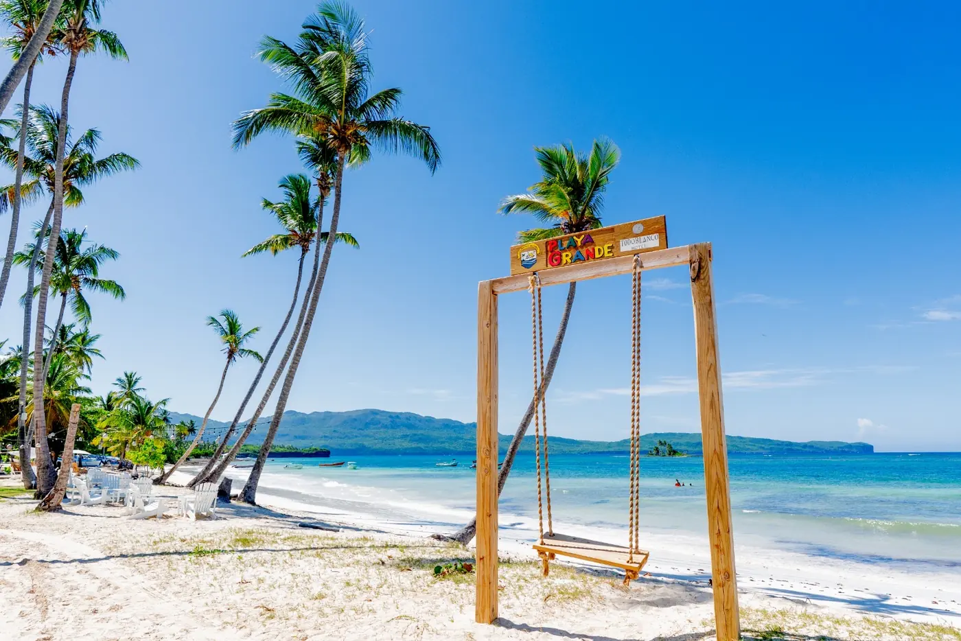 Swing and leaning palms on the white sand of Playa Grande, Las Galeras
