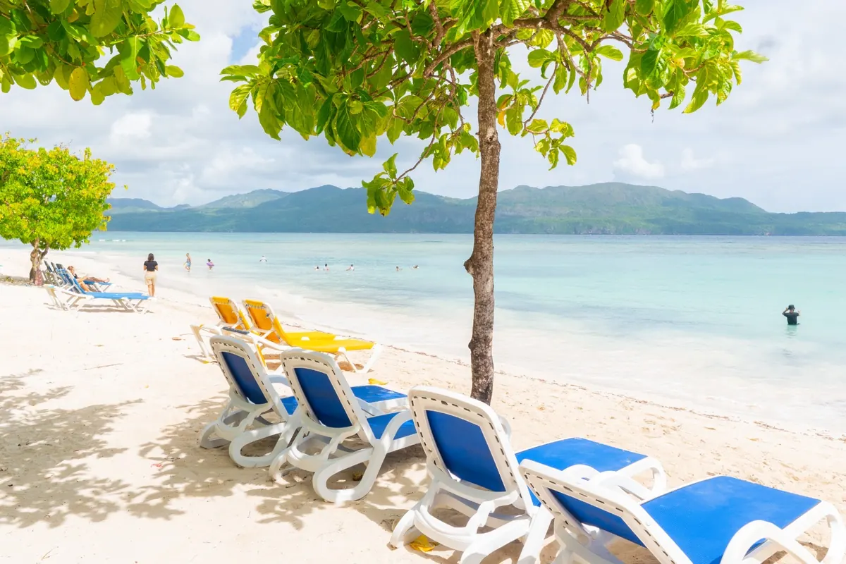 Sun loungers in the shade facing the calm bay and the mountains